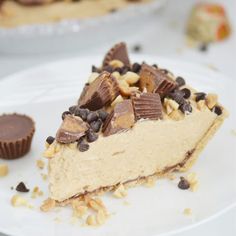 a piece of pie on a white plate with chocolate chips and peanut butter pieces next to it