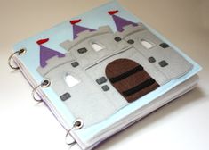 an open book with a castle on the front and purple turrets on the back, sitting on a white surface