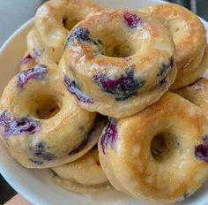 blueberry donuts stacked on top of each other in a white bowl, ready to be eaten