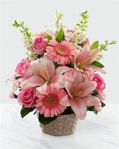 a basket filled with lots of pink flowers on top of a white marble countertop