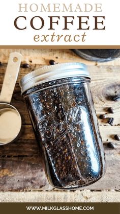 a mason jar filled with homemade coffee next to a spoon and cup on a wooden table