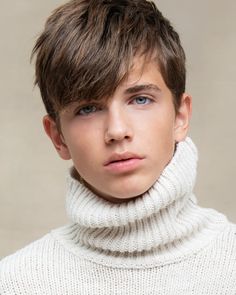 a young man with short hair wearing a turtle neck sweater and looking at the camera