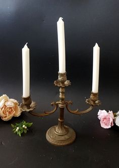 three candles are sitting on a table with flowers