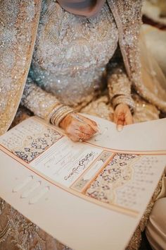 a woman in a wedding dress is holding an open book and writing on the pages