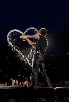 a man standing on top of a stage holding a microphone in front of a heart