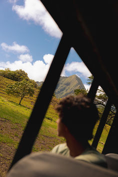 a man riding on the back of a bus down a lush green hillside