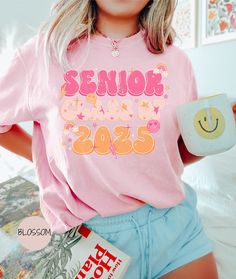 This retro Senior Class of 2025 shirt by Comfort Colors is as trendy as it is comfortable! It would be a great gift for the soon to be 2025 high school graduate in your life! COMFORT COLORS DETAILS: .: Soft-washed, garment-dyed fabric  .: Double-needle stitching throughout  .: 100% ring-spun cotton .: Medium fabric (6.1 oz/yd² (206.8 g/m .: Relaxed fit .: Sewn-in twill label CARE INSTRUCTIONS: .:Machine wash cold; do not bleach. Dry on low heat or lay flat to dry; do not dry clean. SIZING .:This Senior Shirts, Class Of 2025, Retro T Shirt, Photoshoot Outfits, Retro Tshirt, Dyed Fabric, Sweater Shop, Comfort Colors, Lay Flat