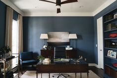 a living room with blue walls and a ceiling fan in the middle of the room