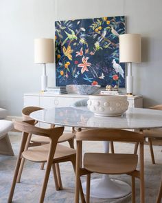 a dining room table with chairs and a painting on the wall