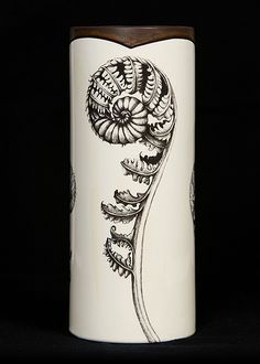 a white vase with black and brown designs on it's sides, against a black background