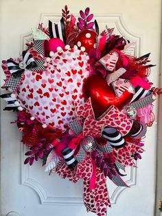 a valentine's day heart wreath hanging on the front door with hearts and ribbons