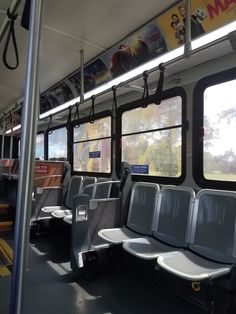 the inside of a bus with empty seats and posters on the wall above it's windows