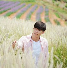 a young man is standing in the middle of a field with lavenders behind him