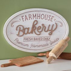 a sign that says farmhouse bakery on the side of a counter next to a rolling pin