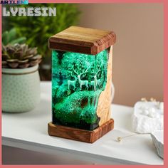 a wooden stand with a green light in the middle on top of a table next to a potted plant