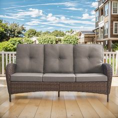 a couch sitting on top of a wooden floor next to a white fence and building