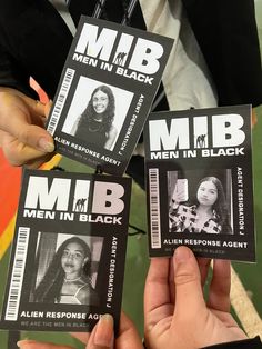 three people holding up some black and white id cards with women in black on them