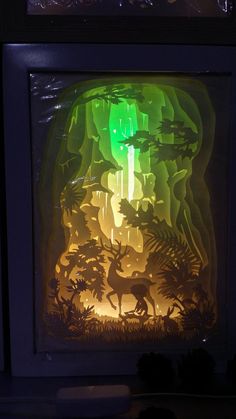 the shadow of an animal in front of a lit up window with trees and animals on it