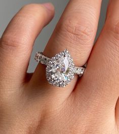 a woman's hand with a diamond ring on top of her finger and an engagement band