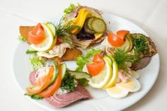 a white plate topped with meat and veggies on top of a white table