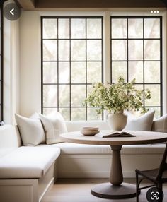 a white couch sitting next to a table in front of a window with lots of windows