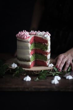 a woman is cutting into a cake with pink and green frosting on the top