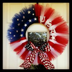 a patriotic wreath with red, white and blue tulle hanging on the front door