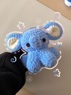 an elephant stuffed animal sitting on top of a person's leg next to a wall