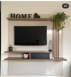 a flat screen tv mounted to the wall above a shelf with plants and vases