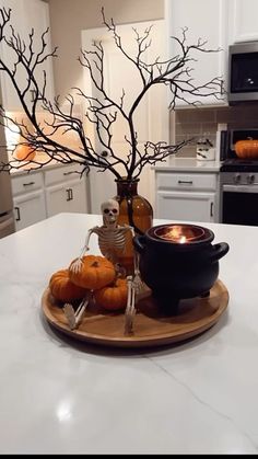 a white kitchen counter top topped with a bowl filled with pumpkins next to a tree