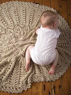 a baby laying on top of a crocheted rug with the words home and garden essentials written below it