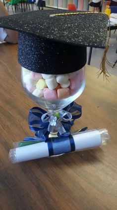 a graduation cap is sitting on top of a candy filled glass jar with marshmallows in it