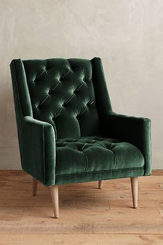 a green chair sitting on top of a hard wood floor next to a white wall