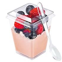 a container filled with berries and yogurt next to a spoon