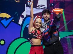 a man and woman standing next to each other on stage holding an orange frisbee