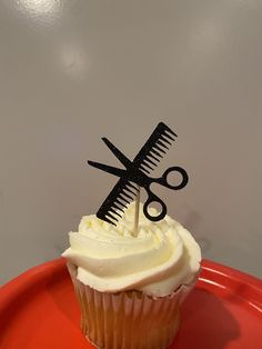 cupcake with white frosting and black scissors on top