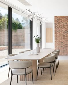 a dining room table with chairs and a potted plant in the center, next to a brick wall