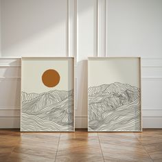 two framed art pieces on the floor in an empty room