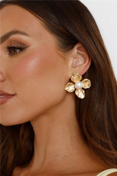 a woman wearing gold earrings with pearls