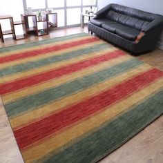 a living room with a black leather couch and striped rug