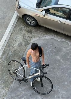 a shirtless man standing next to his bike