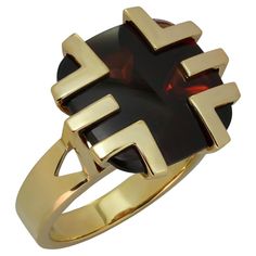 This gorgeous Cartier cocktail ring is crafted in 18k yellow gold and features a cabochon garnet set in a geometric crown. The 14.7mm x 14.9mm buff-top cushion-shaped garnet has dark red color with brownish tones, a fairly good transparency with some inclusion visible upon close inspection, and surface wear in form of fine scratches visible upon close inspection. Made in France circa 1970s. Measurements: 0.66" (17mm) width, 0.66" (17mm) length. The ring size is 6.25 - EU 53. Resizable. Sizing fees will be provided upon request. Geometric Crown, Ring Pictures, 18k Yellow Gold Ring, Yellow Gold Ring, Cocktail Ring, Cocktail Rings, Yellow Gold Rings, Dark Red, Cartier