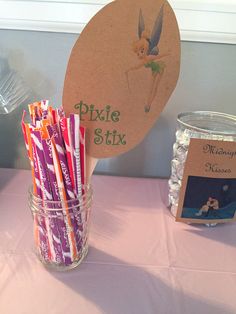 there is a jar with candy sticks in it and a sign on the table that says pixie six