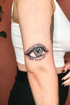 a woman's arm with an eye and heart tattoo on the left side of her arm