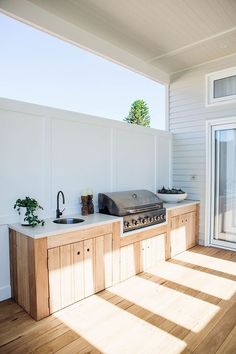 an outdoor kitchen with wood flooring and white walls