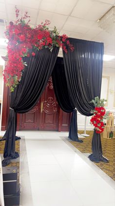 a room decorated with black drapes and red flowers