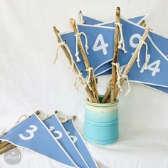 a blue vase filled with sticks and numbers on top of a white cloth covered table