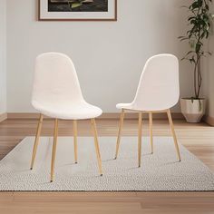 two white chairs sitting next to each other on top of a rug in a room