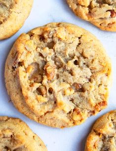 several cookies are on a white surface with crumbs and nuts in the middle