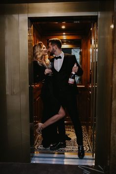 a man in a tuxedo and a woman in a black dress are standing on an elevator